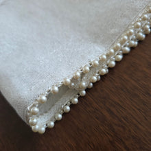 Closeup detail of the Pearl Embelllished Challah Cover in a natural white woven fabric background with subtle silver flecks. Enlargement shows the smaller and larger alternating pearl beads trimming the outside edges.